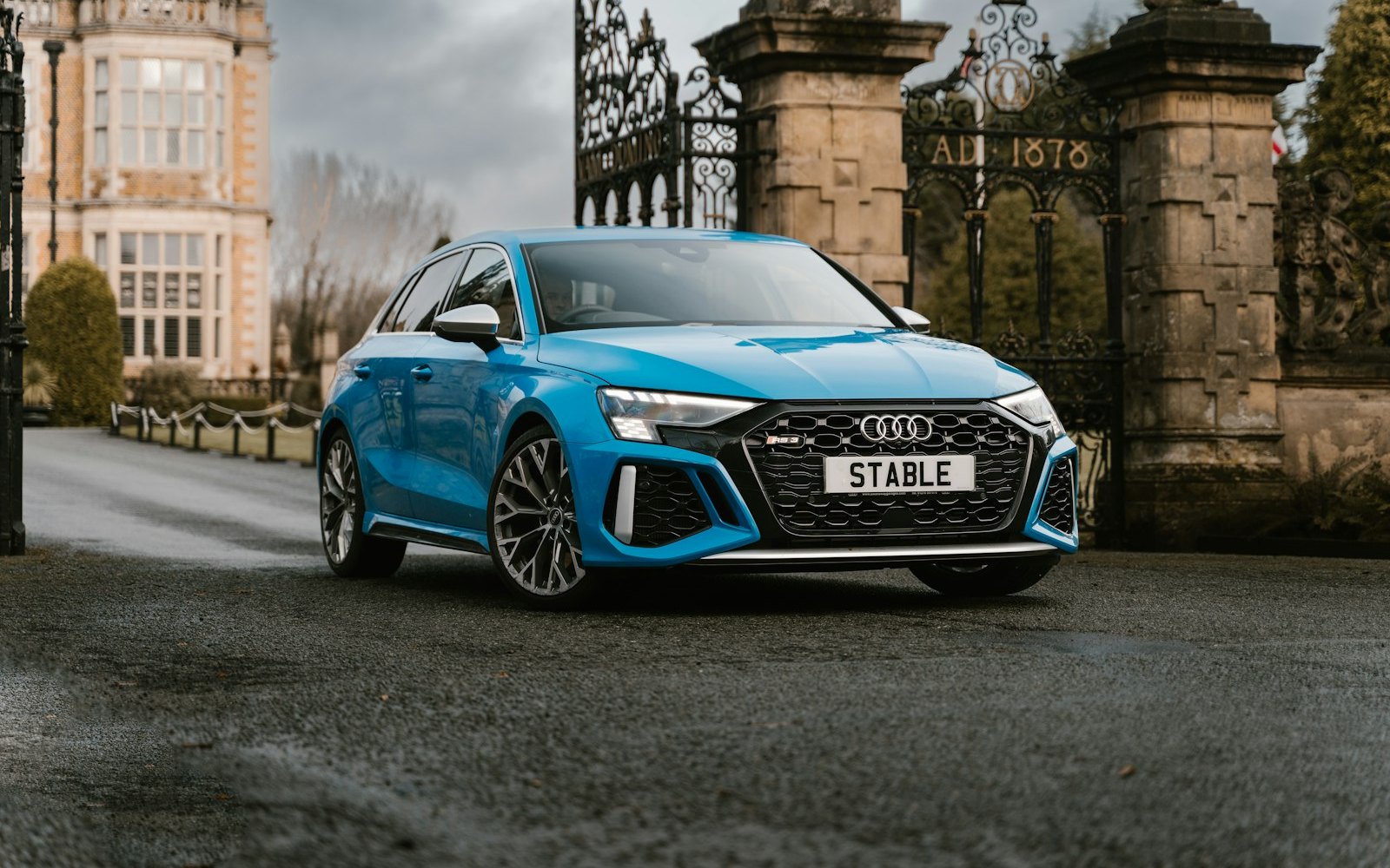 Blue Audi RS3 8Y Sportback in front of stone gates