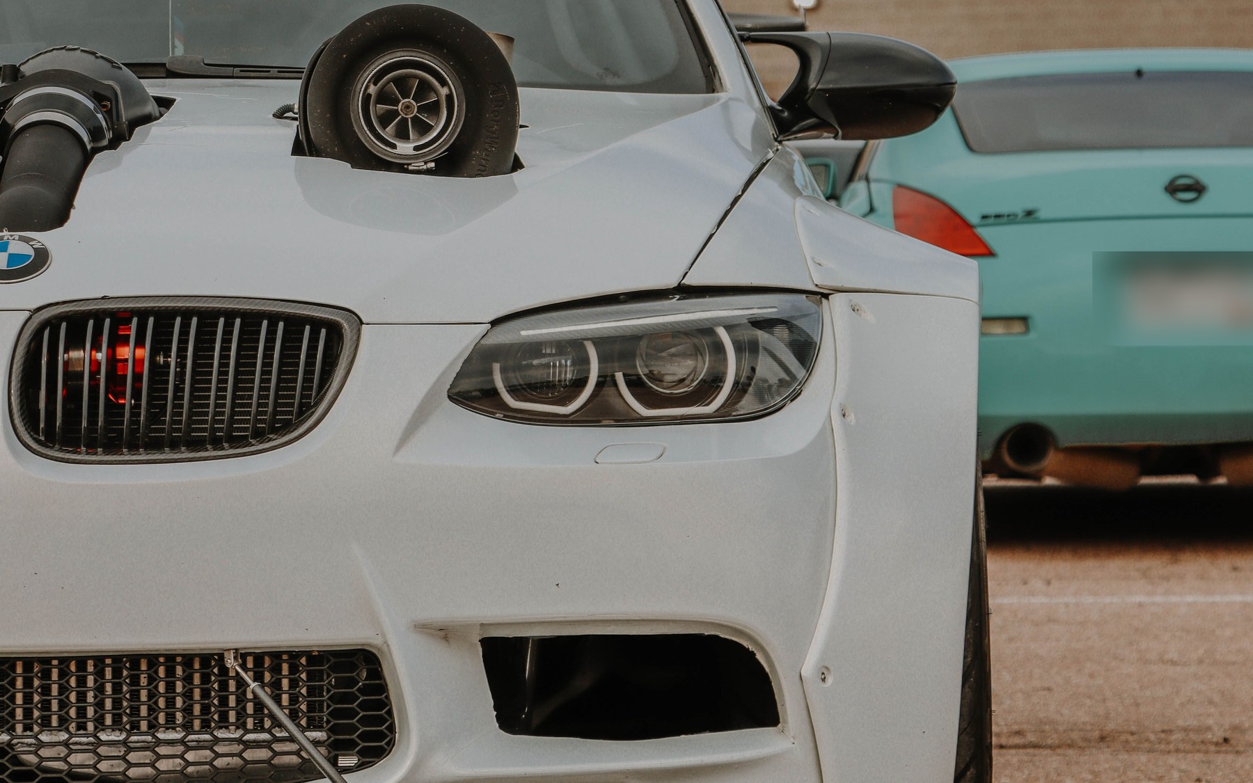 Доработанная белая BMW 3 серии E92 с одной турбиной, торчащей из капота, расширенными арками и бампером в стиле M3