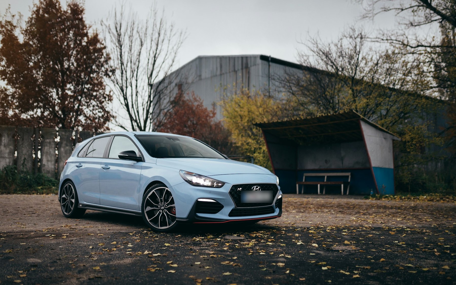 Performance Blue Hyundai i30 N hatchback parked by autumn trees