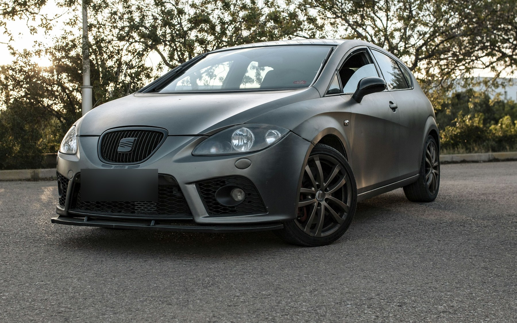 Modified grey Seat Leon Mk2 with a front splitter, dark aftermarket wheels and red calipers, number plate blurred